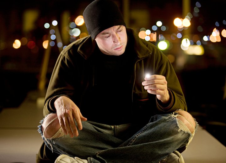 Nate sitting outdoors at night, city lights behind him