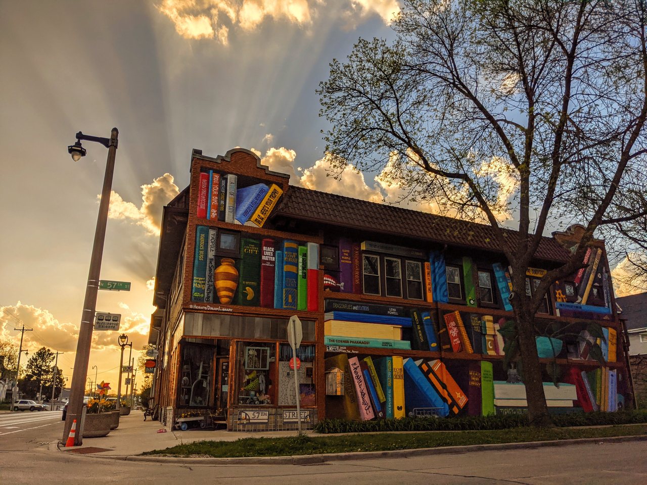 A building painted as a shelf of giant books, sunbeams behind it