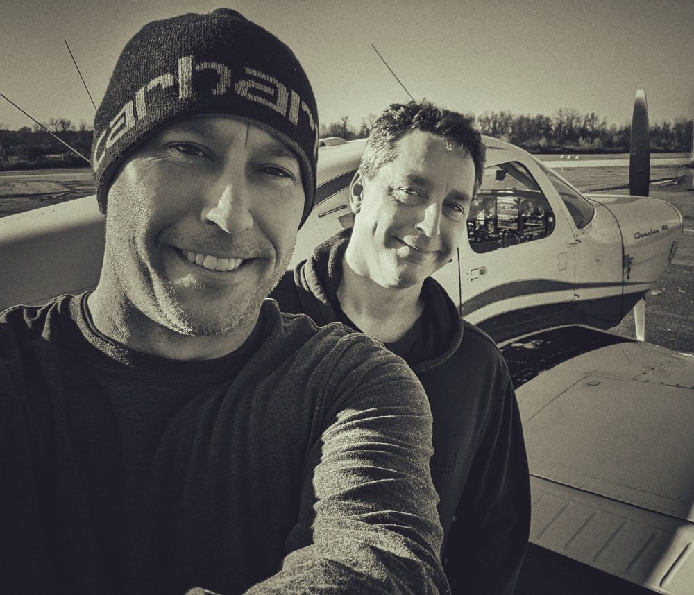 Nate and a friend by a small plane, black and white